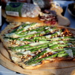 Opskrift på tarte flambée med creme fraiche, asparges, parmesan og pinjekerner